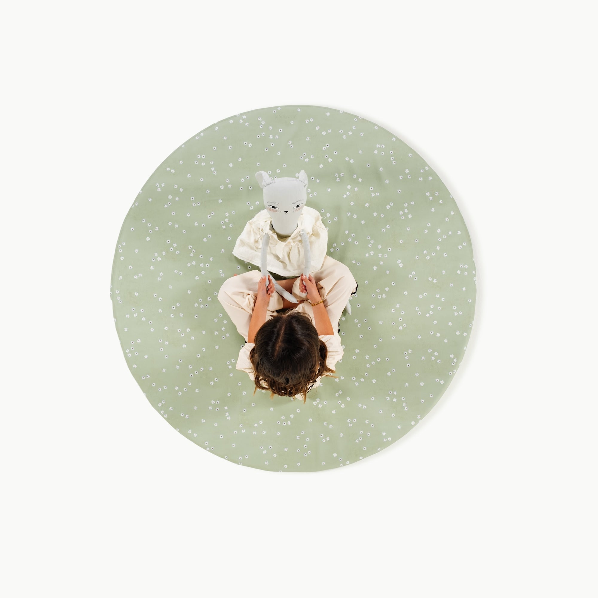 Flora@overhead of little girl sitting on padded mat