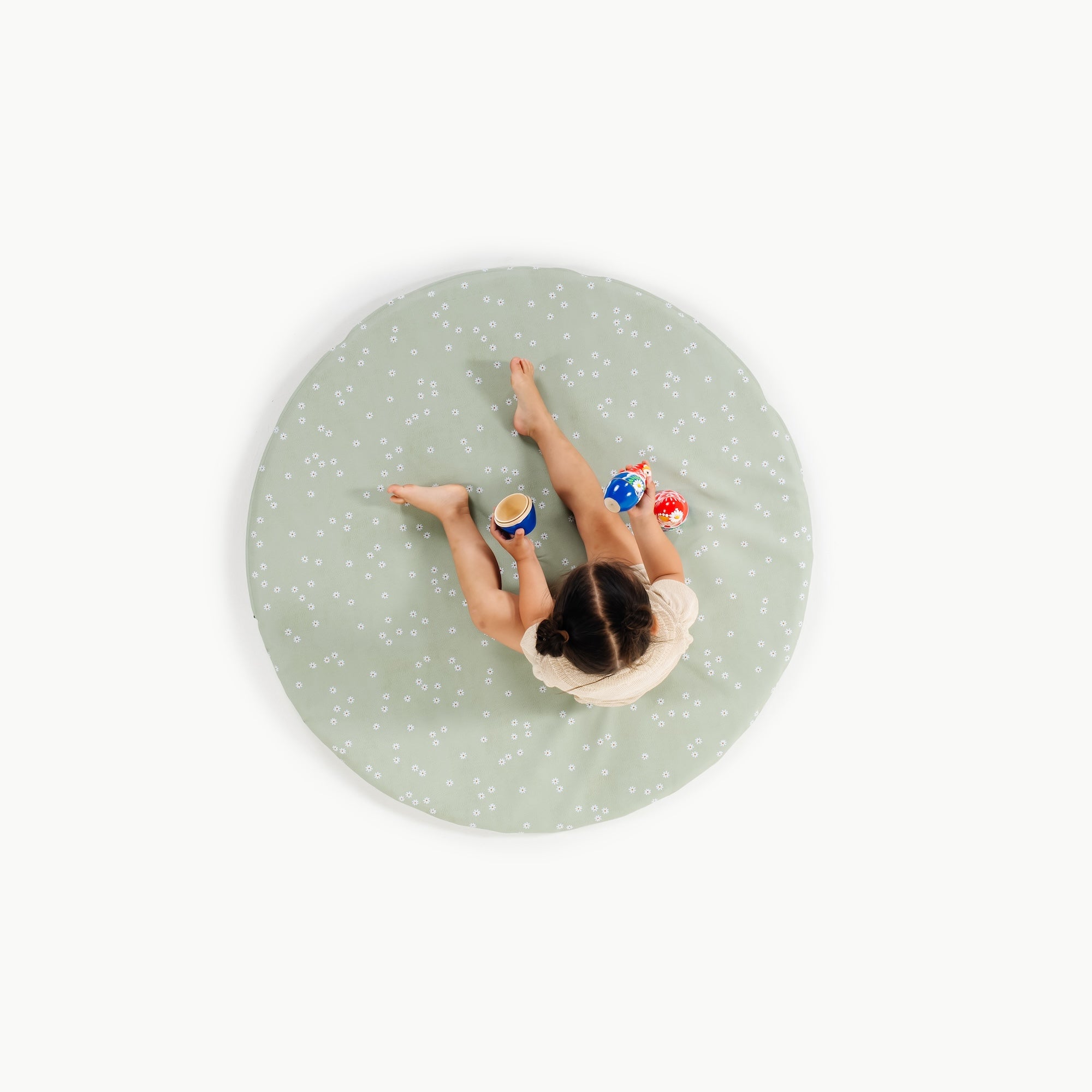 Flora / Circle@overhead of little girl playing on padded mat