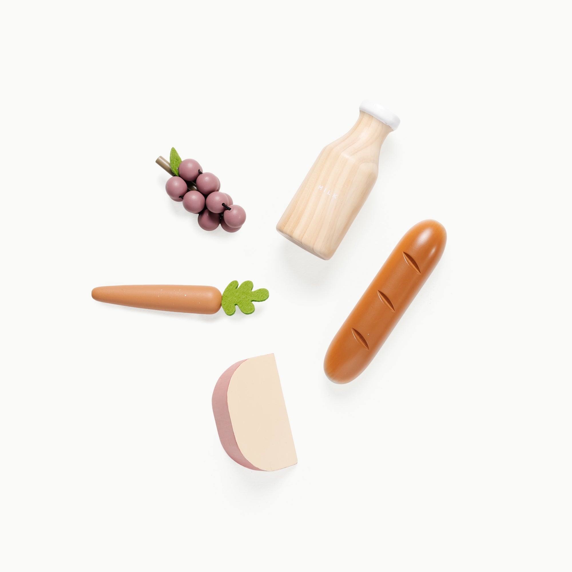 toy grapes, milk, bread, cheese and a carrot, laid out in a circle