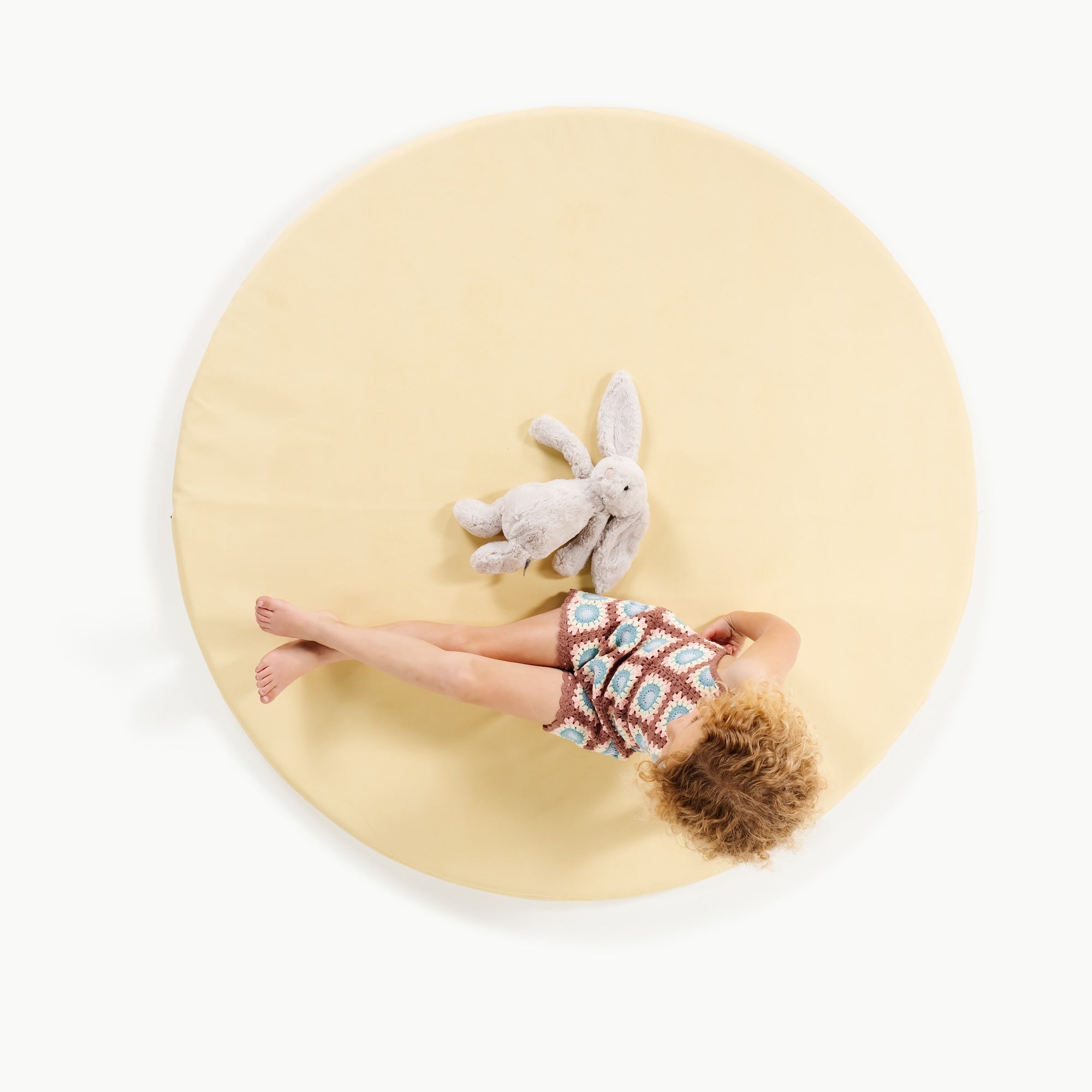 Mellow@overhead of little girl sitting on padded mat