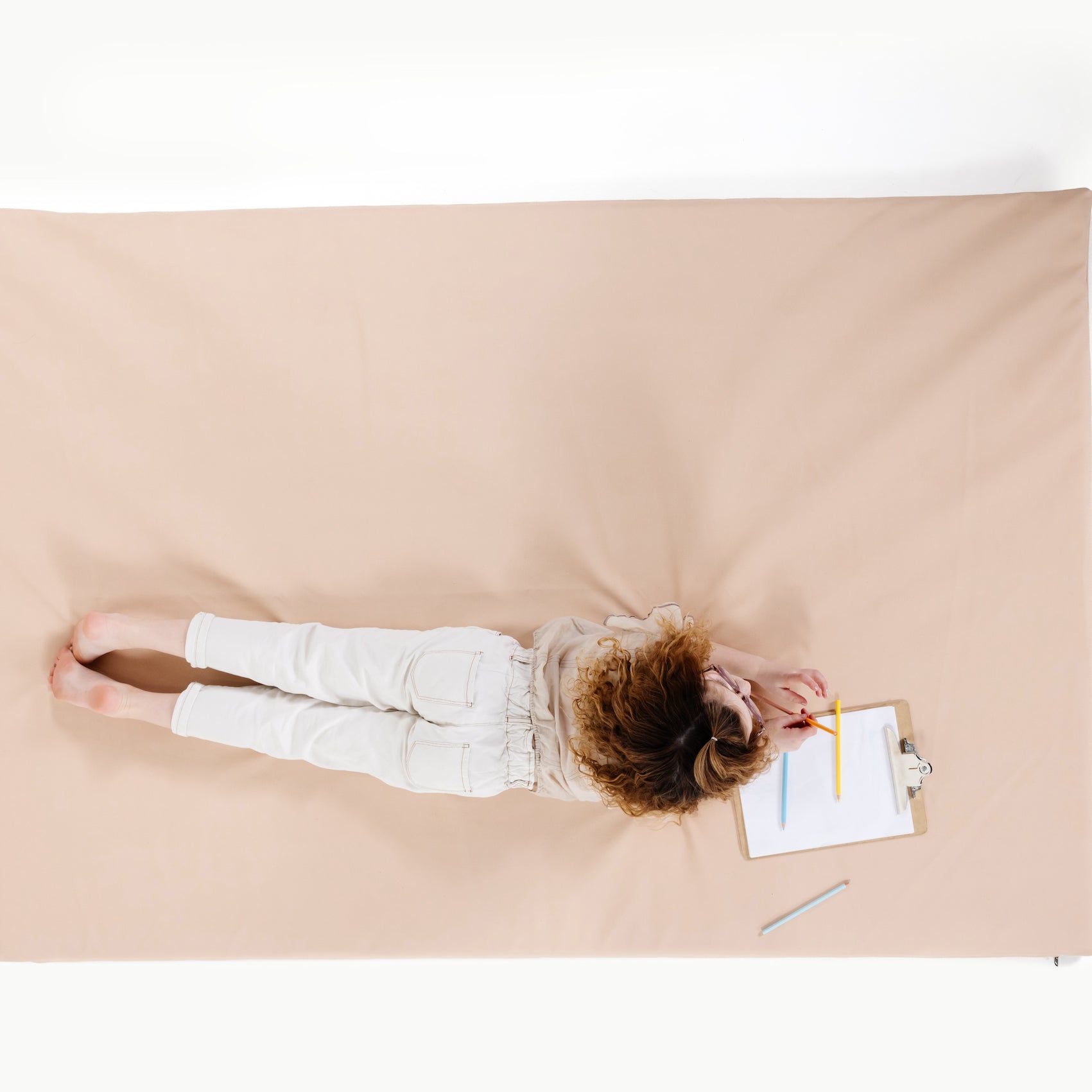 Pomelo (on sale)@overhead of kid laying on the pomelo padded midi+ mat