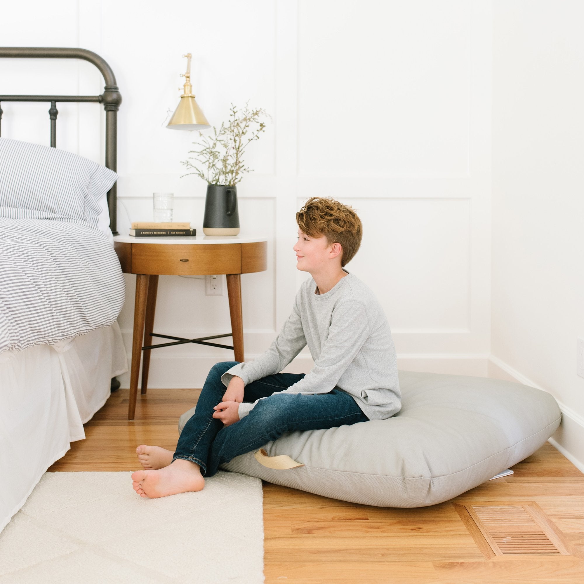 Pewter (on sale) / Square@Kid sitting on the Pewter Square Floor Cushion in a bedroom