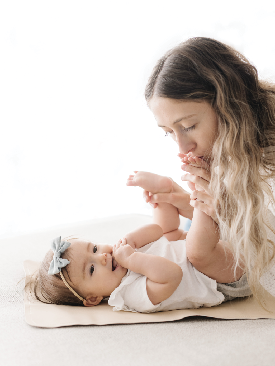 Baby on micro mat with Mom kissing their feet.