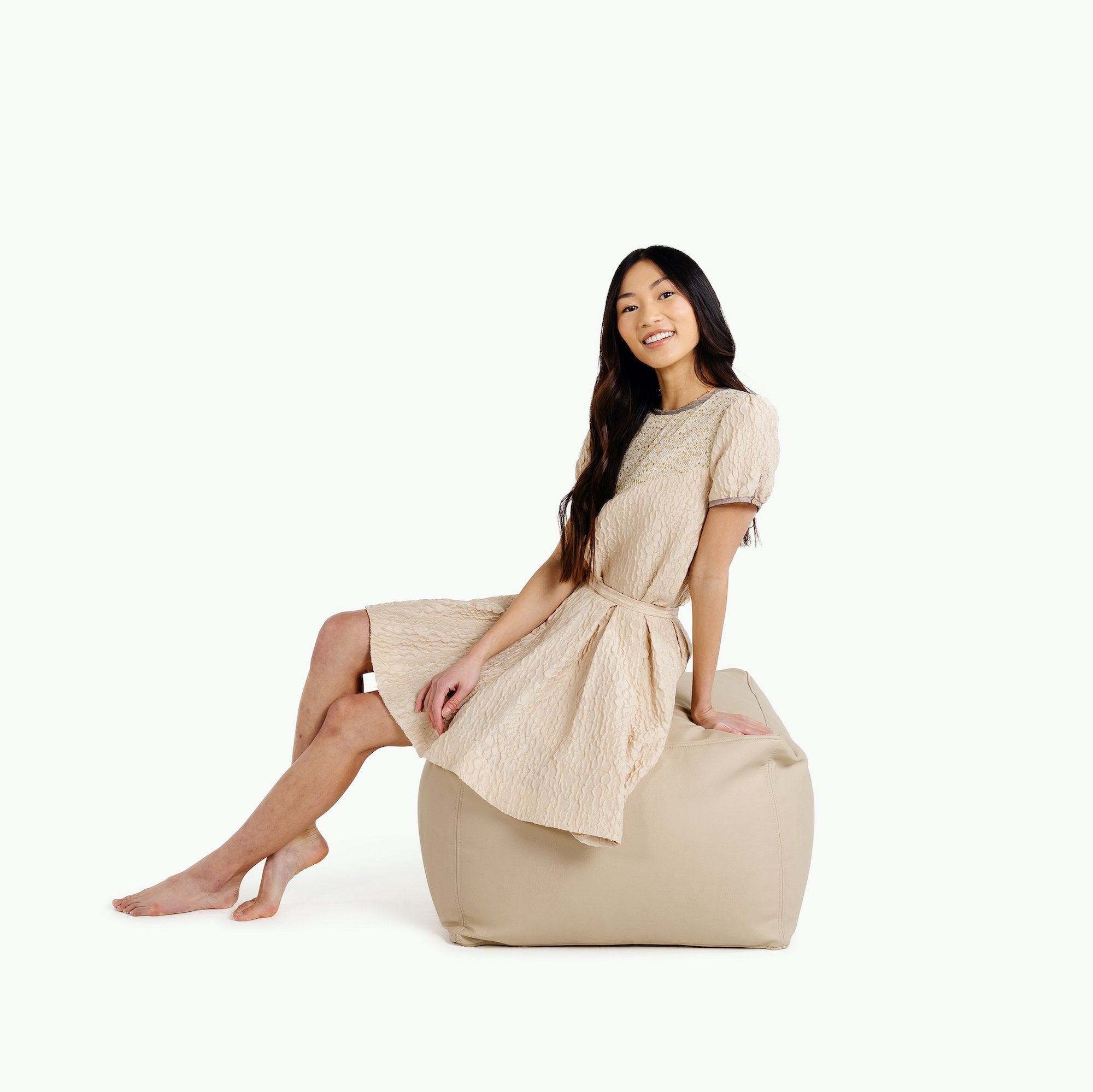 Millet@woman sitting on the Millet Square Pouf