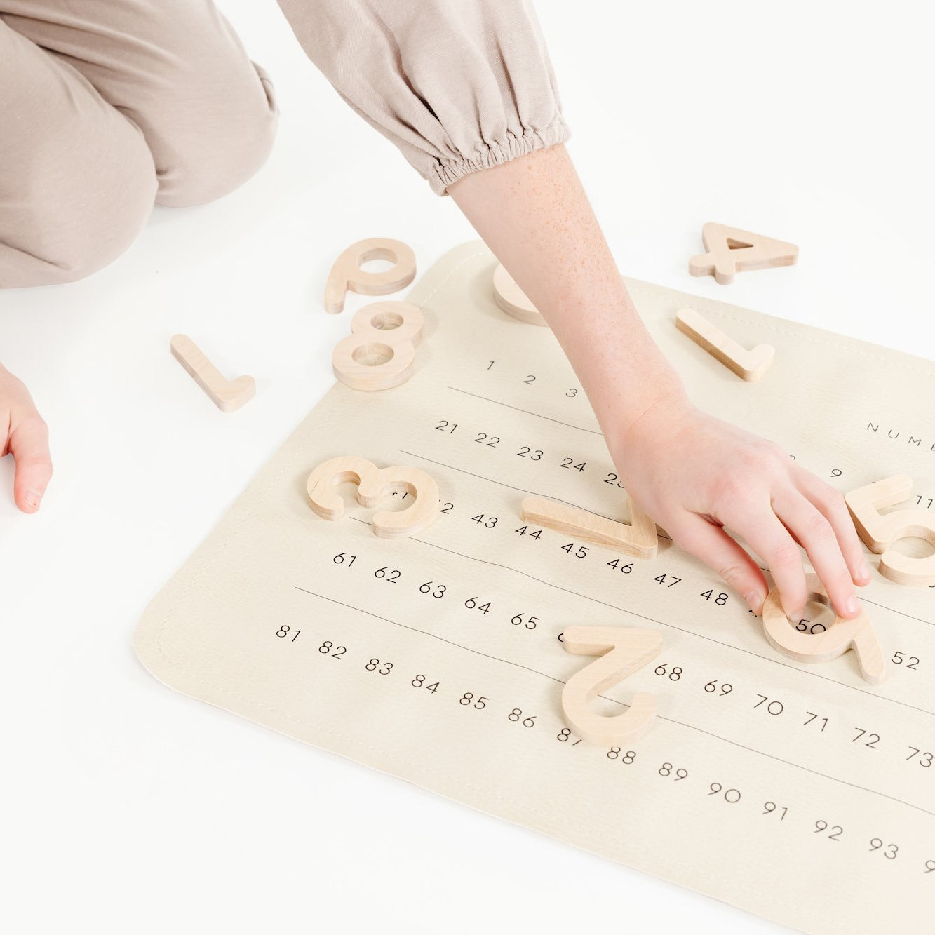 Numbers (on sale)@Childs hand playing with Wooden Numbers on Numbers Micro Mat