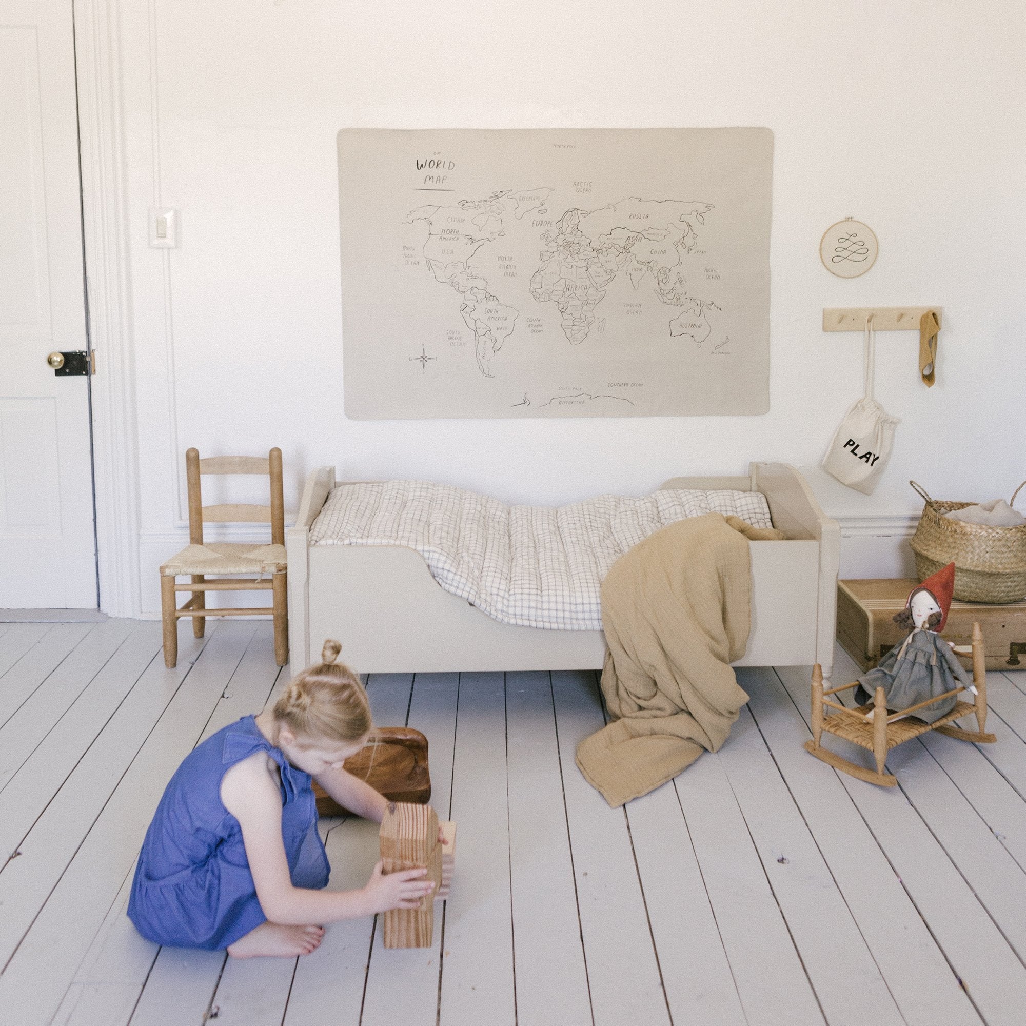 World Map@World Map Mini+ Mat hanging above a bed in a bedroom with a kid playing on the floor