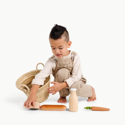 boy playing with grocery toys, laying the food items out in a row