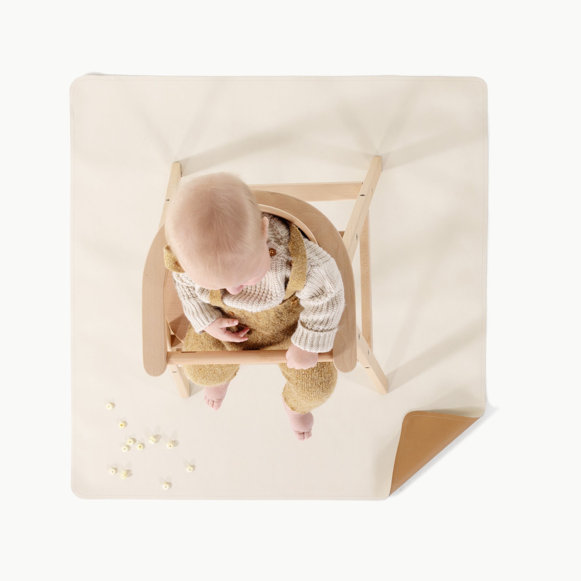 Camel • Ivory@overhead of baby in a high chair on mini mat