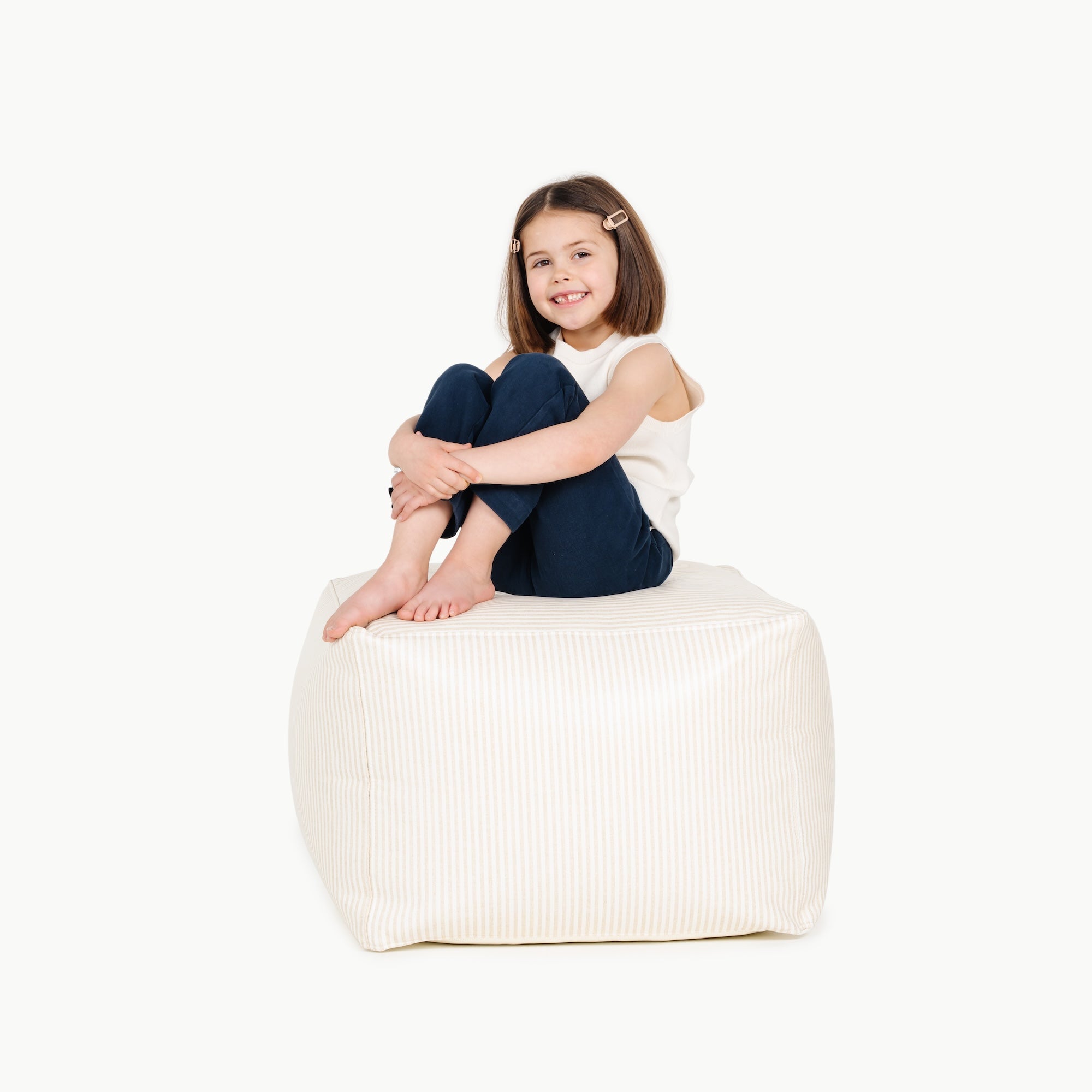 Pinstripe@little girl sitting on a square pouf