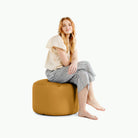 Saffron@woman sitting on a circle pouf