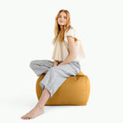 Saffron@woman sitting on a square pouf