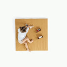 Tassel / Square@overhead of little girl playing on padded mat