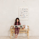 Fleurs@Fleurs Poster hanging in bedroom above a little girl reading on a bench