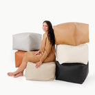Camel / Square@Woman sitting on a Square Pouf surrounded by other Square Poufs  