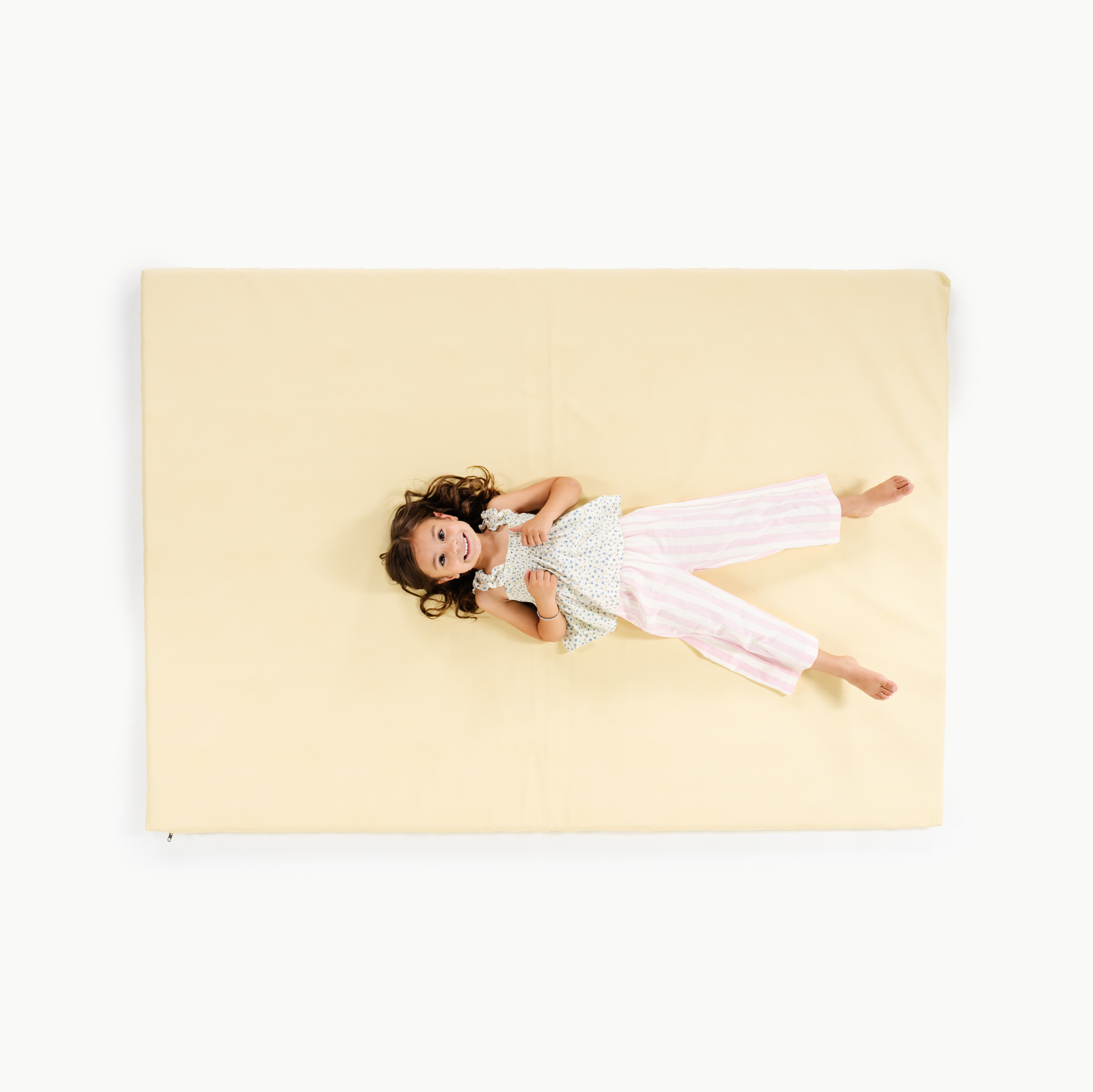 Mellow@overhead of little girl sitting on padded mat