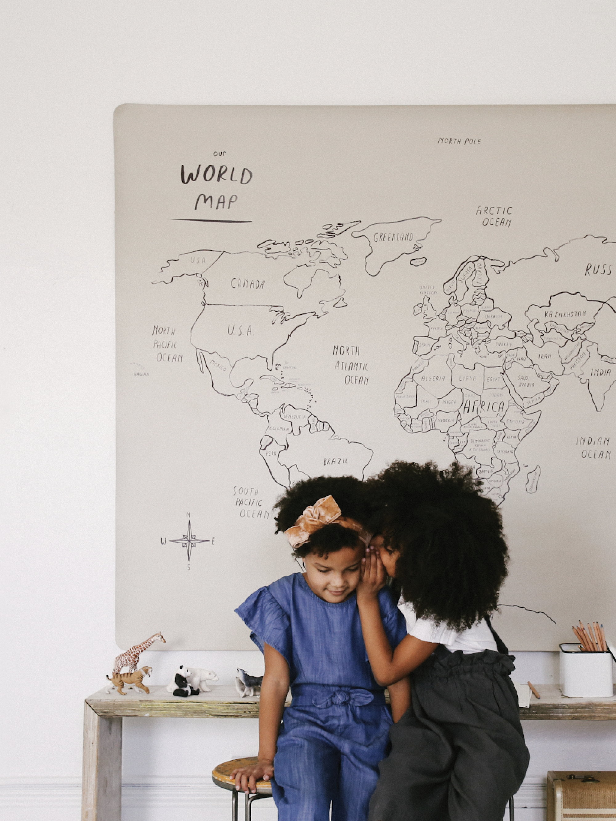 Kids sitting in front of the Midi+ World Map hanging on a wall.