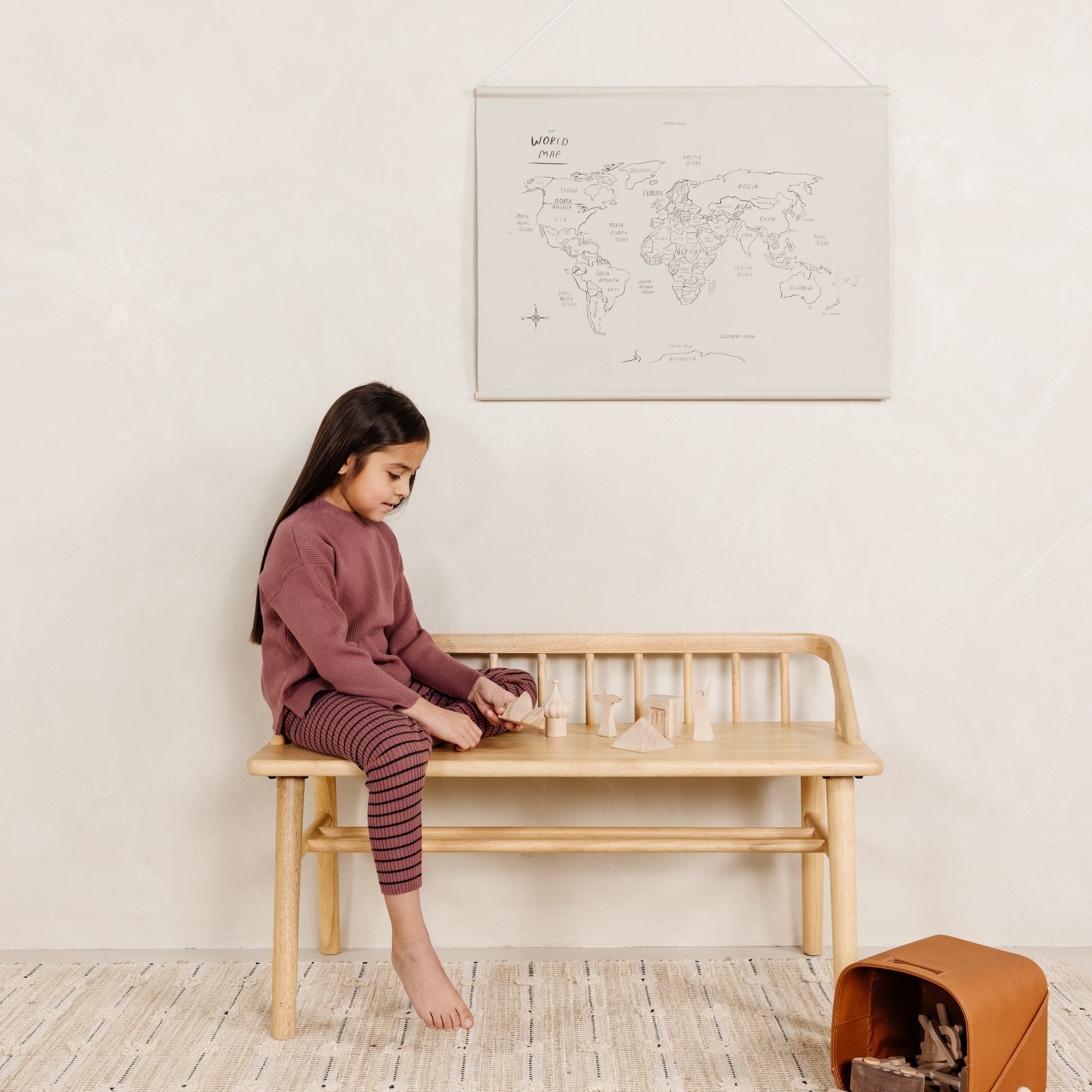 World Map@World Map Poster hangin on wall above little girl playing on a bench